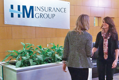 Two women greeting each other in the lobby of HM Insurance Group