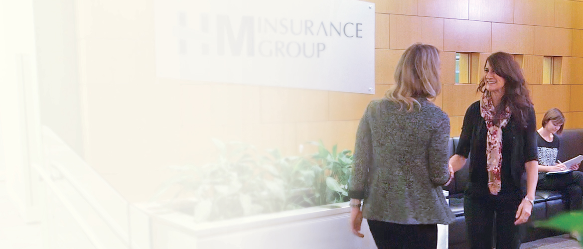 Two women greeting each other in the lobby of HM Insurance Group
