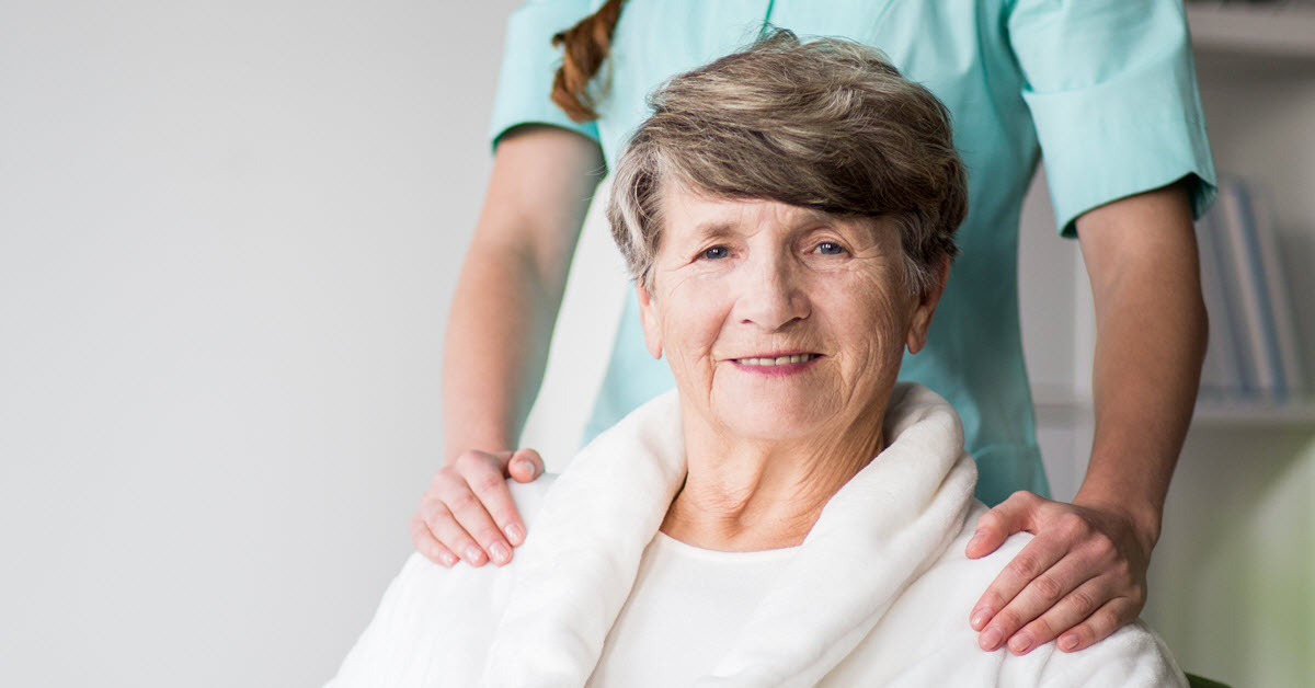 Elderly woman seated with a female doctor standing behind her