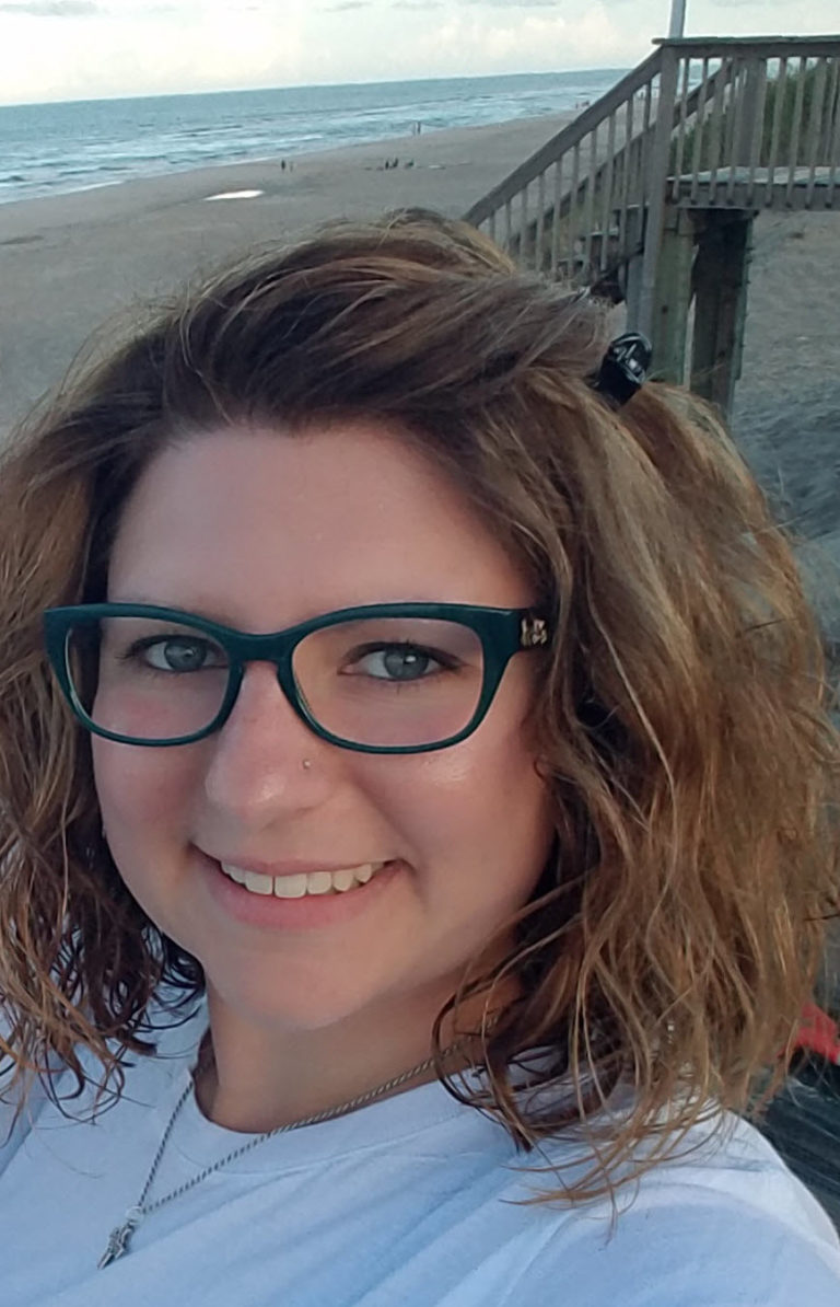 Close-up of smiling Jamie Kwolek with beach in the background