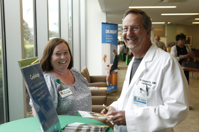 A cardiologist and assistant standing at an information table