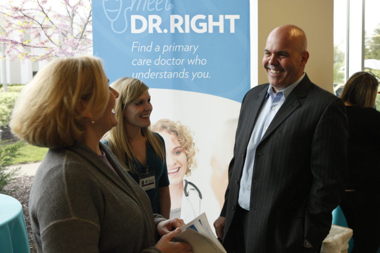 Two visitors laugh as they’re talking with an event representative