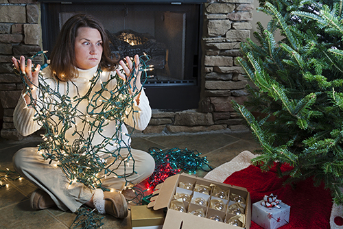 Woman sitting by tree with tangled lights.