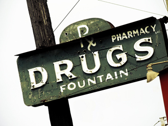 A pharmacy sign that says “Pharmacy Drugs Fountain”