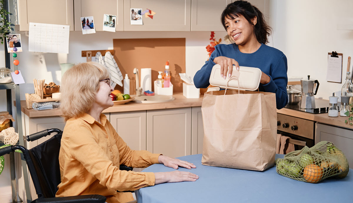Woman delivering food to a senio citizen.
