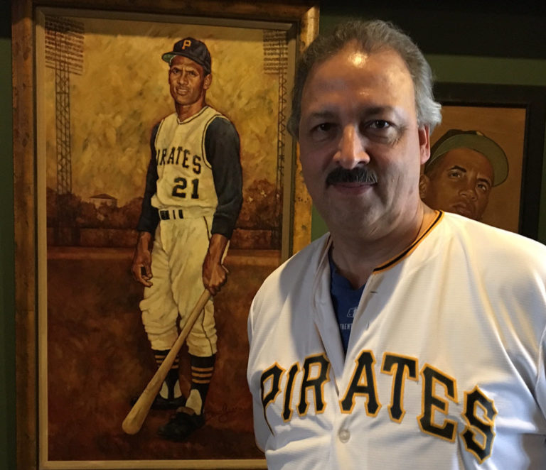 Highmark Health corporate communications SVP Fred Ramos wearing a Pirates shirt and standing in front of a painting of Roberto Clemente at the Clemente Museum in Pittsburgh