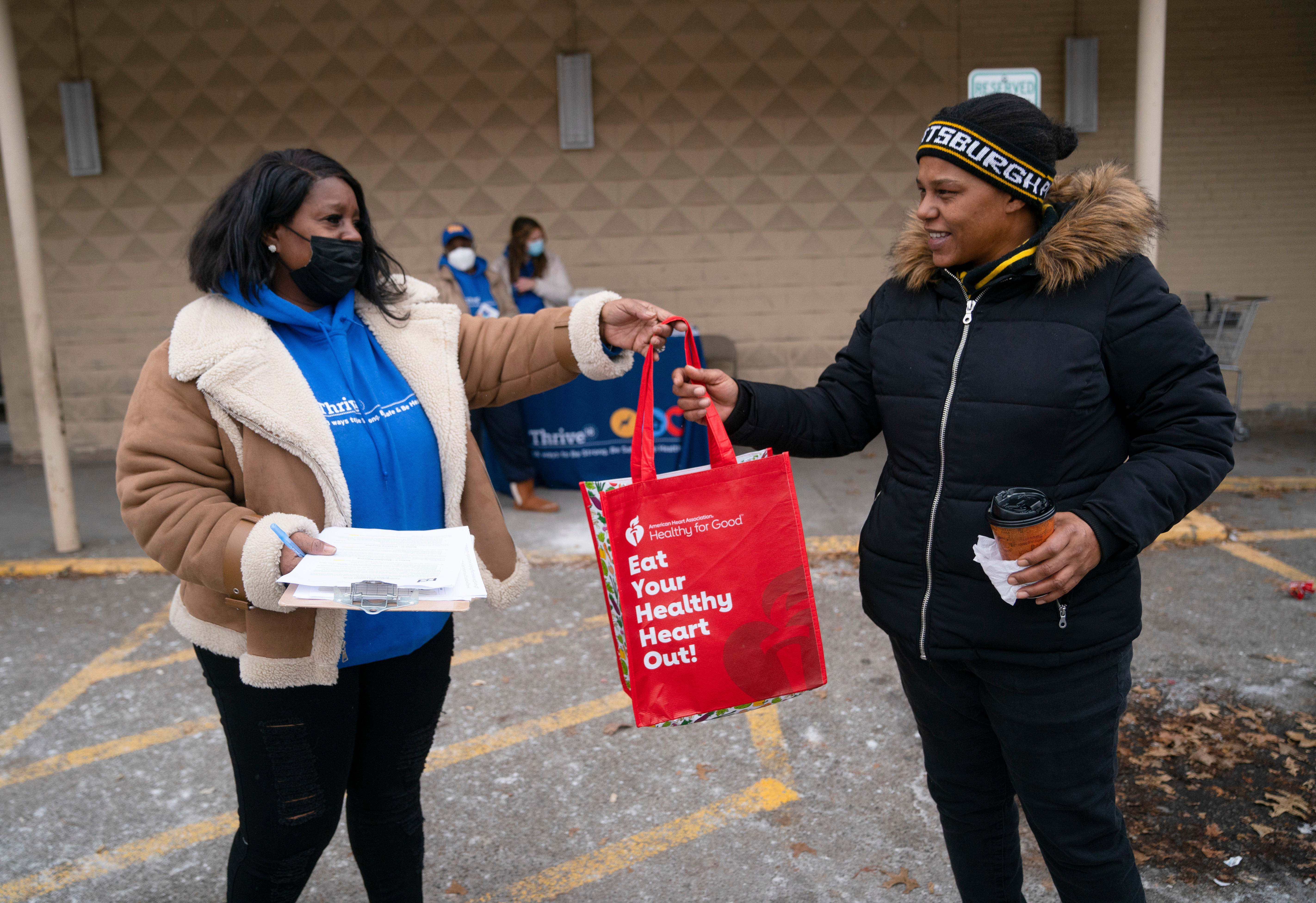 A Thrive18 outreach worker distributes masks and hand sanitizer to North Side residents outside a local grocery store.