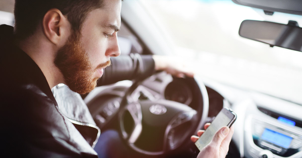 A man looking at his mobile phone while driving