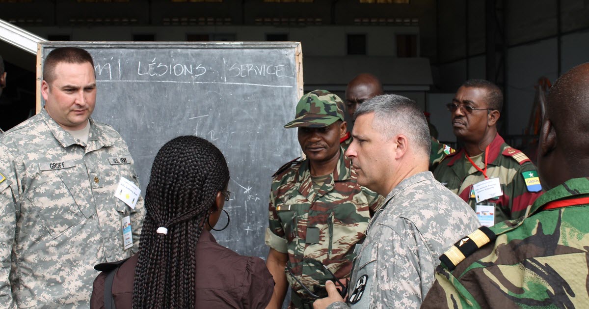 Tony and a group of people in Cameroon, Africa having a discussion in front of a blackboard